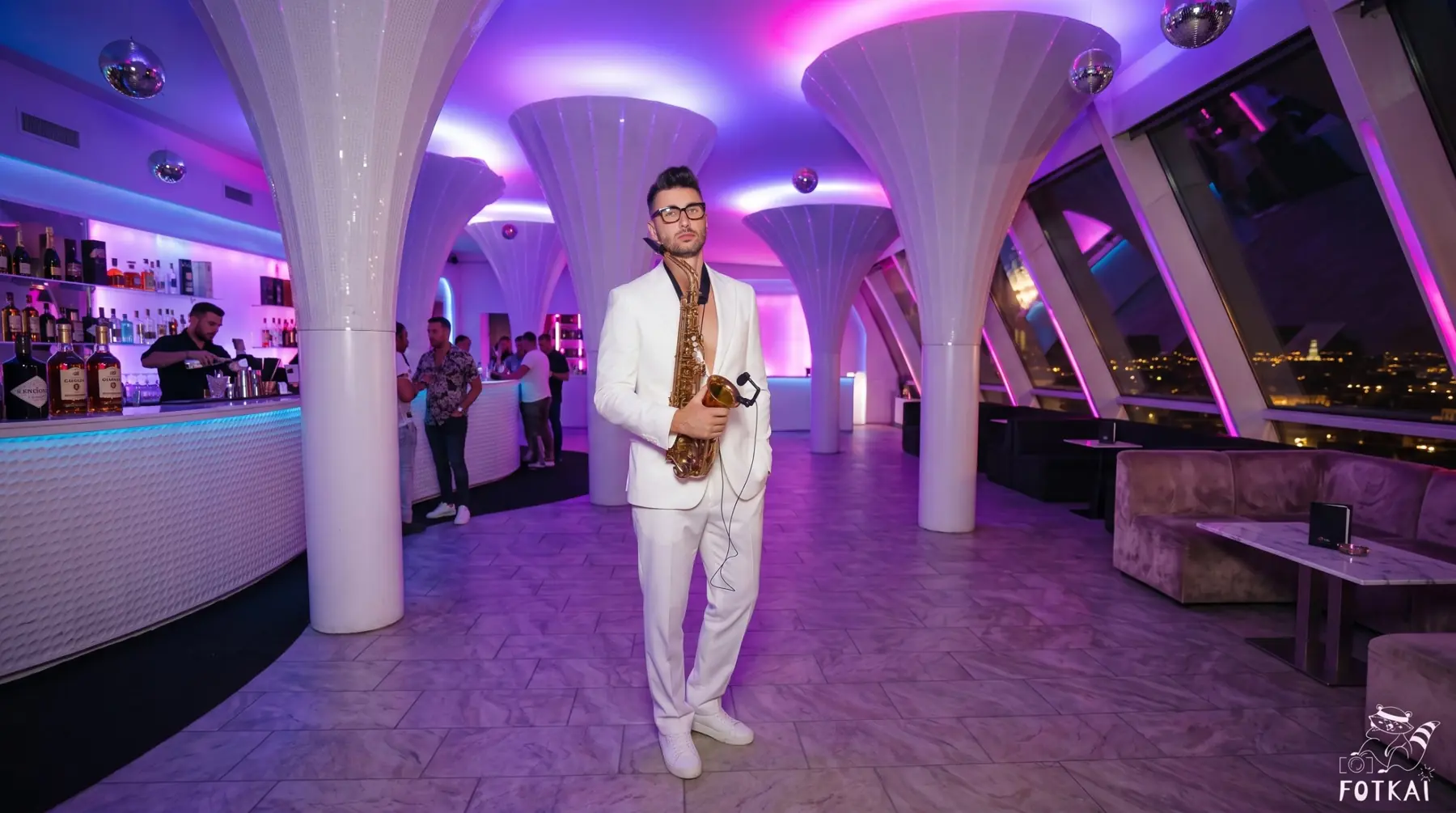 Pablo Leontiev en traje blanco con saxofón en un rooftop