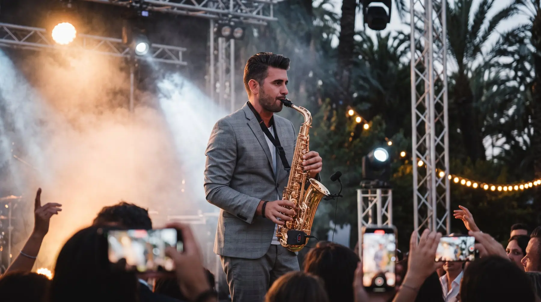 Saxofonista en el escenario con el público grabando con el móvil